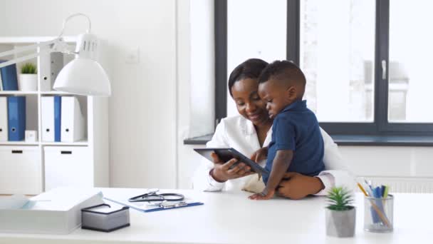 Врач показывает планшет с ребенком пациенту в клинике — стоковое видео