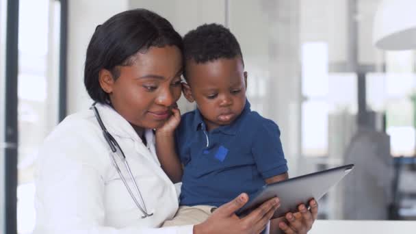 Врач показывает планшет с ребенком пациенту в клинике — стоковое видео