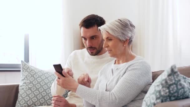 Vieille mère et fils adulte avec smartphone à la maison — Video