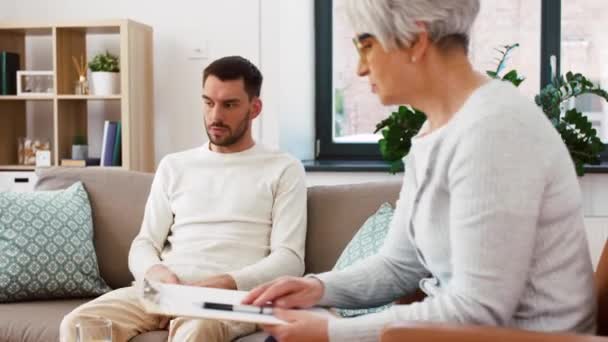 Senior psychologist giving water to man patient — Stock Video