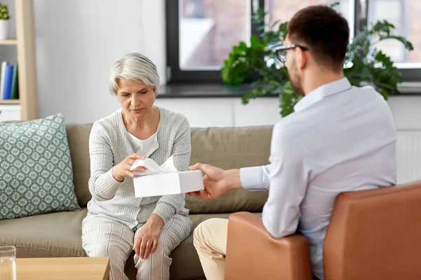 Psicólogo dando tecidos para o cliente mulher sênior — Fotografia de Stock