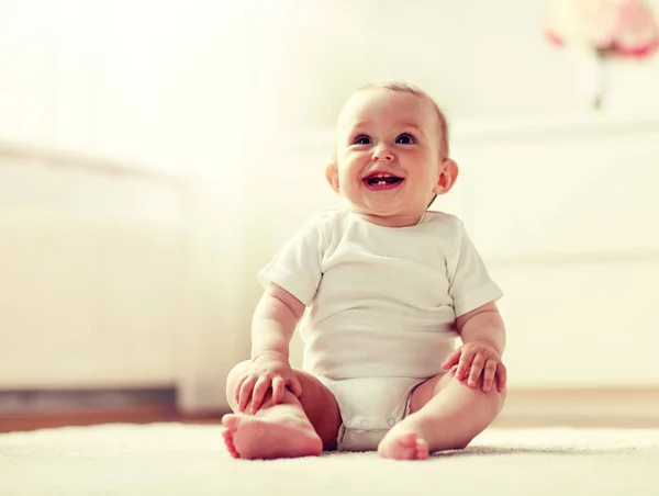 Glücklicher kleiner Junge oder Mädchen, die zu Hause auf dem Boden sitzen — Stockfoto