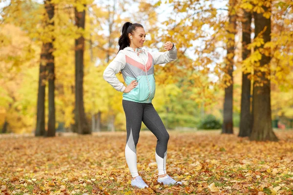 Kobieta patrząc na fitness tracker w jesiennym parku — Zdjęcie stockowe