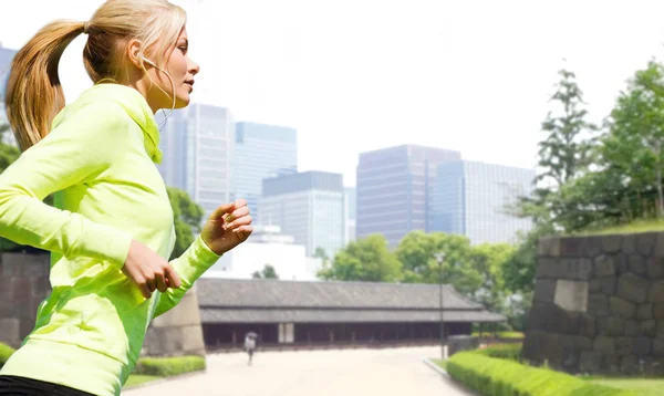 都市公園で走っているイヤホンを持つ女性 — ストック写真