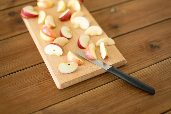 Tranches de pommes et couteau sur planche à découper en bois — Photo