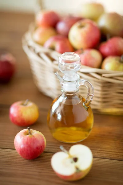 Äpfel im Korb und Krug mit Essig auf dem Tisch — Stockfoto