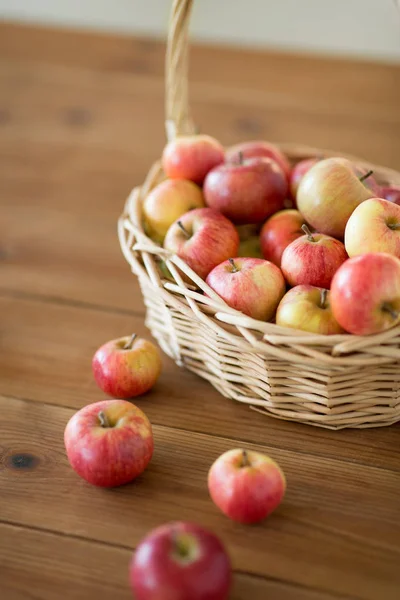 Ripe apples in wicker basket on wooden table — Stock Photo, Image