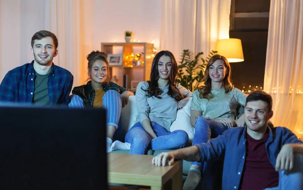 Amigos felizes assistindo tv em casa à noite — Fotografia de Stock