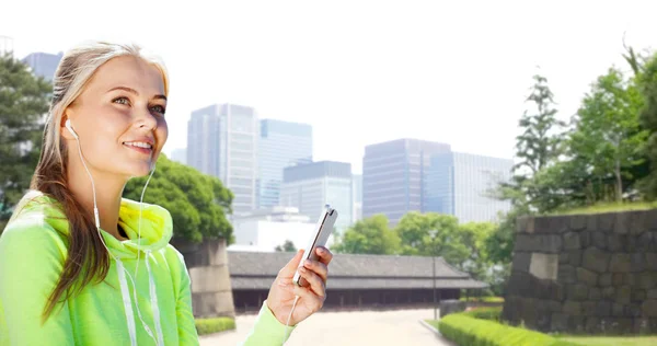 Kvinna lyssnar på musik på smartphone på City — Stockfoto