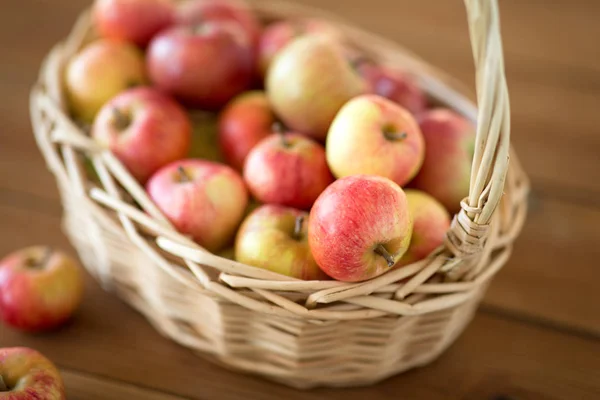 Ripe apples in wicker basket on wooden table — Stock Photo, Image