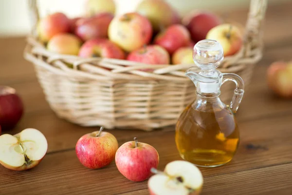 Äpfel im Korb und Krug mit Essig auf dem Tisch — Stockfoto