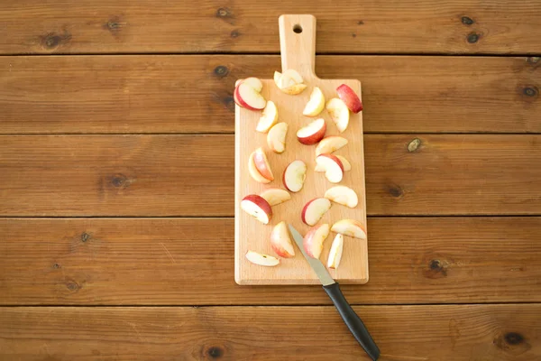 Tranches de pommes et couteau sur planche à découper en bois — Photo