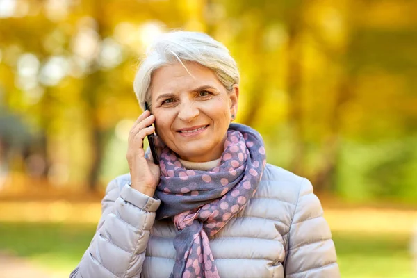 Seniorin telefoniert mit Smartphone im Herbstpark — Stockfoto