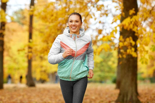 Genç kadın sonbahar parkında koşuyor. — Stok fotoğraf