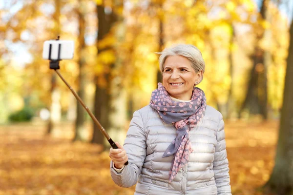 Seniorin macht Selfie im Herbstpark — Stockfoto