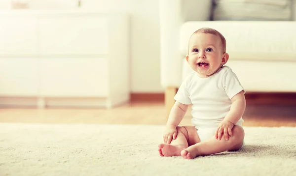 Boldog kisfiú vagy lány ül a padlón otthon — Stock Fotó