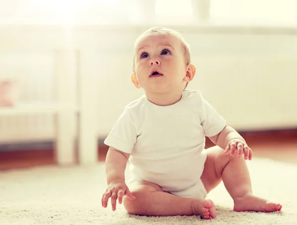 Happy baby boy or girl sitting on floor at home — Stock Photo, Image
