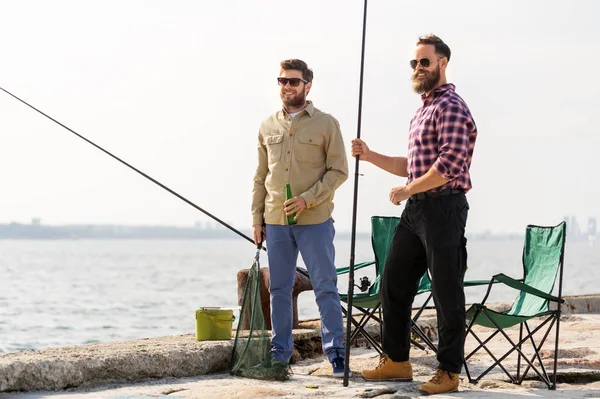 Amigos do sexo masculino com varas de pesca e cerveja no cais — Fotografia de Stock
