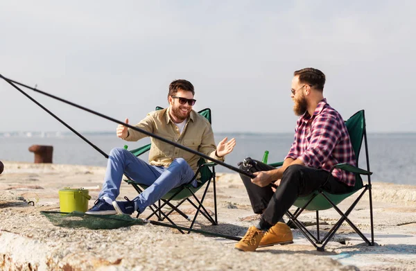 Felizes amigos do sexo masculino com hastes falando sobre pesca — Fotografia de Stock