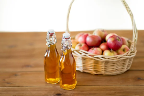 Äpfel im Korb und Saftflaschen auf dem Tisch — Stockfoto