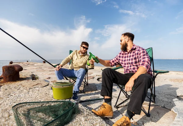 Amigos do sexo masculino pesca e beber cerveja no cais do mar — Fotografia de Stock