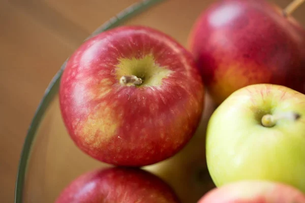 Dojrzałe jabłka w szklanej misce na drewnianym stole — Zdjęcie stockowe