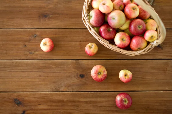 Pommes mûres dans un panier en osier sur une table en bois — Photo