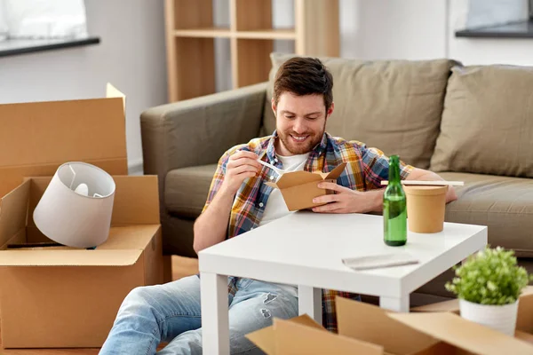 Усміхнений чоловік їсть їжу в новому будинку — стокове фото