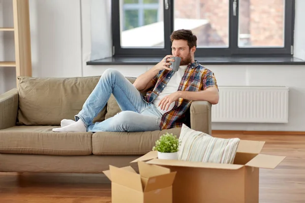 Hombre con cajas y beber café en casa nueva —  Fotos de Stock