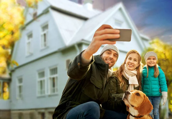 Family with dog taking selfie over house in autumn — Stock Photo, Image