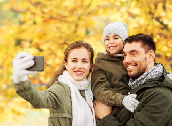Family taking selfie by smartphone in autumn park — Stock Photo, Image