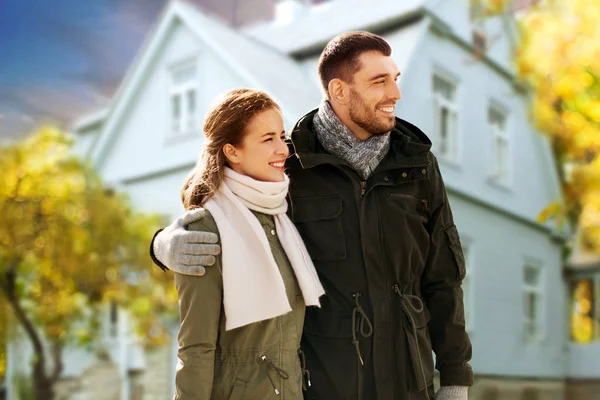 Sonriente pareja abrazándose sobre casa en otoño —  Fotos de Stock