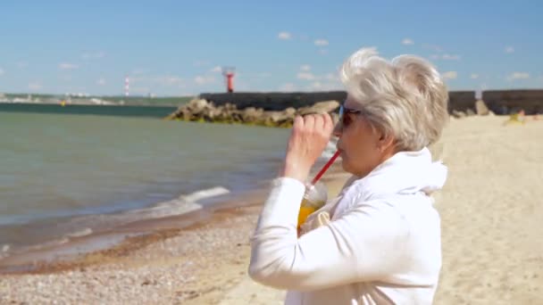 Seniorin trinkt Shake am Sommerstrand — Stockvideo