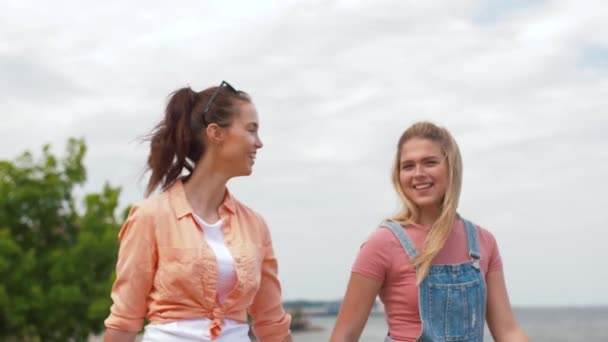 Adolescentes o amigos caminando a la orilla del mar — Vídeo de stock
