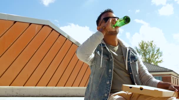 Indyjski człowiek jedzenia pizzy i picia piwa na zewnątrz — Wideo stockowe