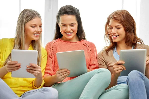 Drie lachende tienermeisjes met tablet pc thuis — Stockfoto