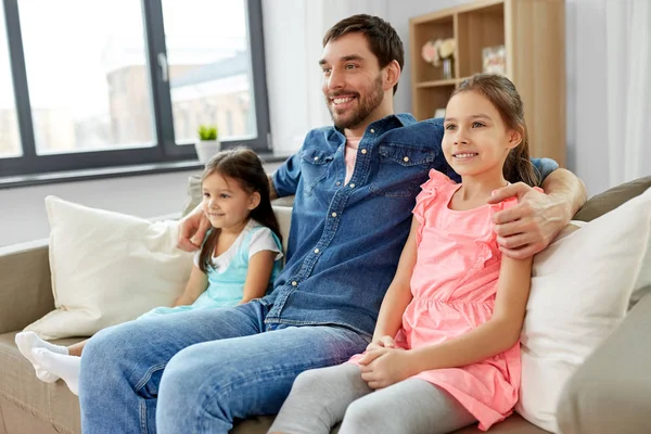Щасливий батько з дочками на дивані вдома — стокове фото