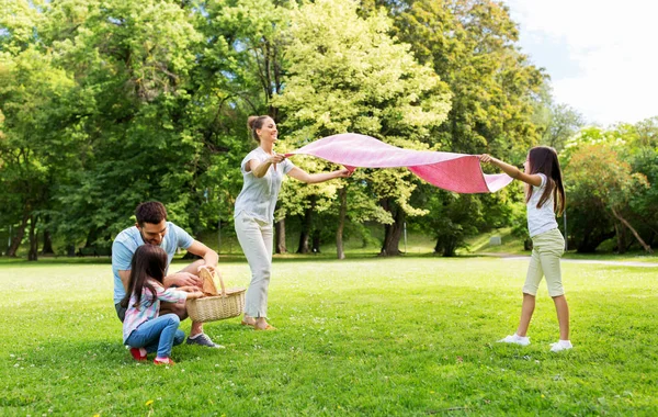 Rodina skládající piknikovou deku v letním parku — Stock fotografie