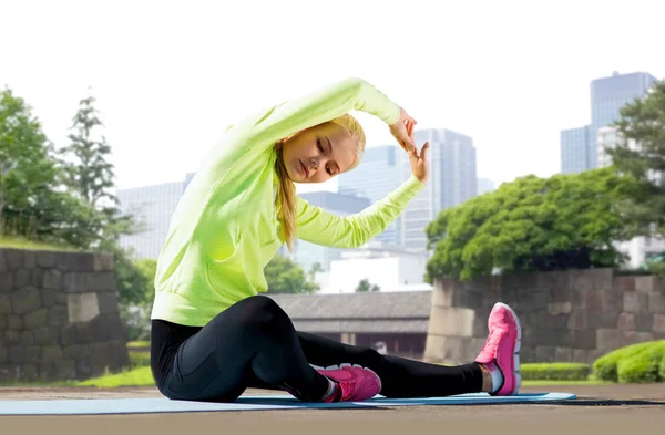 Femme étirant sur tapis d'exercice au parc de la ville — Photo