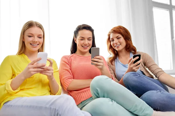 Три девочки-подростка со смартфонами дома — стоковое фото