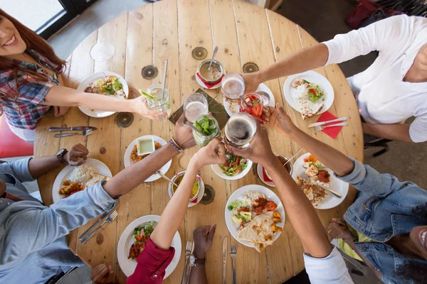 Amici mangiare e bicchieri di clinking al ristorante — Foto Stock