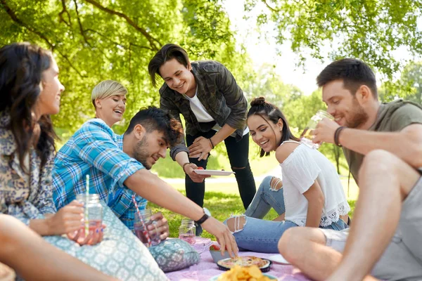 Amigos con bebidas y comida en el picnic en el parque — Foto de Stock