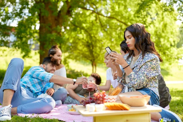 Vrouw met behulp van smartphone op picnic met vrienden — Stockfoto