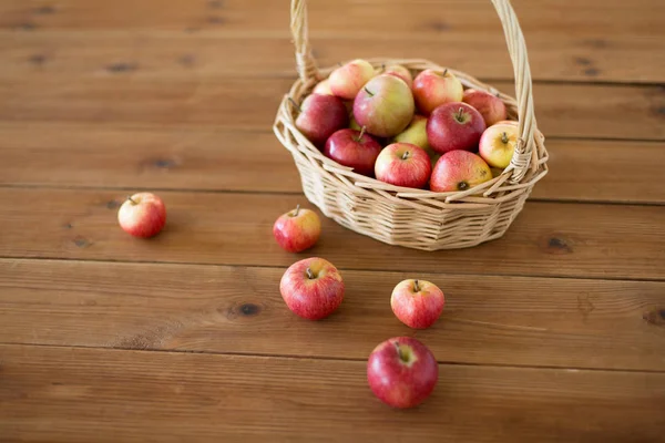 Pommes mûres dans un panier en osier sur une table en bois — Photo
