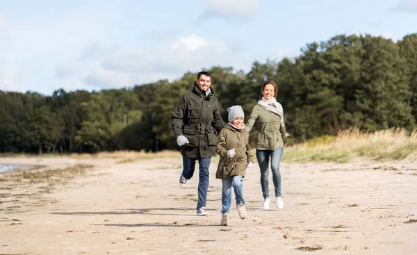 Gelukkige familie loopt langs herfst strand — Stockfoto