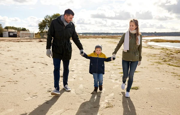 Família feliz andando ao longo da praia de outono — Fotografia de Stock