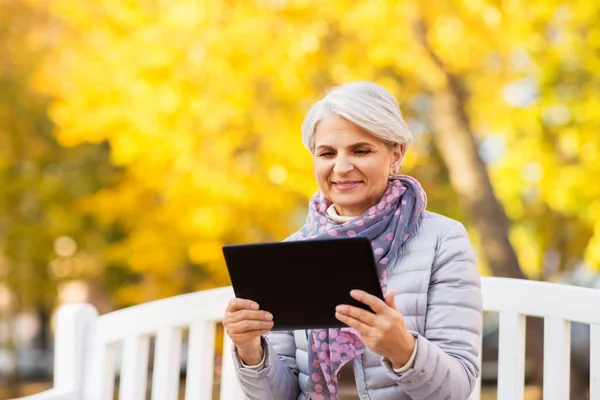 Senior vrouw met tablet pc in zomerpark — Stockfoto