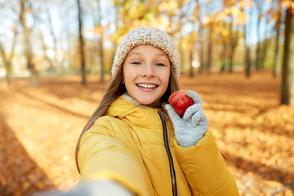 Lycklig tjej med äpple tar Selfie på höst parken — Stockfoto