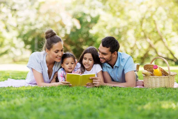 Family reading book on picnic in summer park — Stock Photo, Image