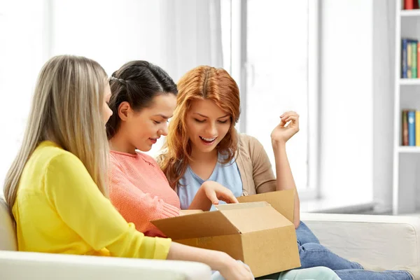 Teenage girls or friends opening parcel box — Stock Photo, Image